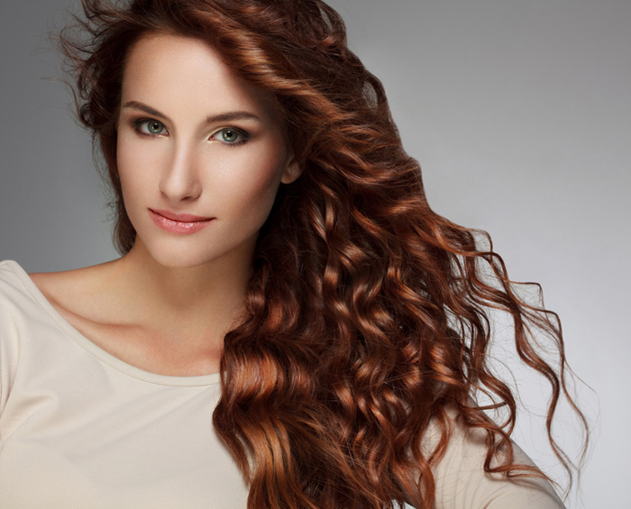 Red Hair. Beautiful Woman with Curly Long Hair. High quality image.